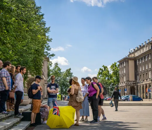 Eine geführte Touristengruppe erkundet einen sonnigen Stadtplatz in Krakau, Polen.