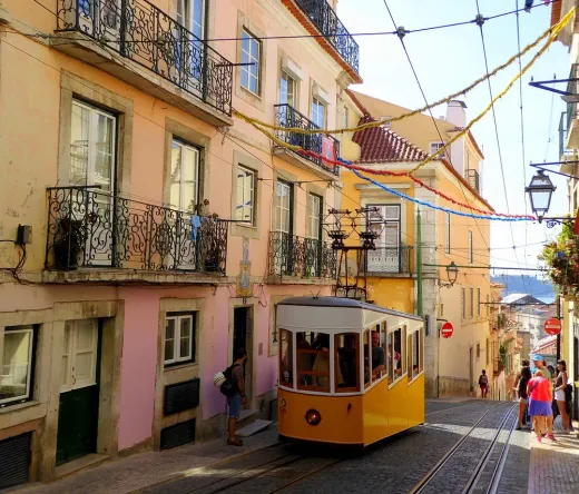Un tranvía amarillo sube una colina en los distritos de Alfama y Mouraria de Lisboa.