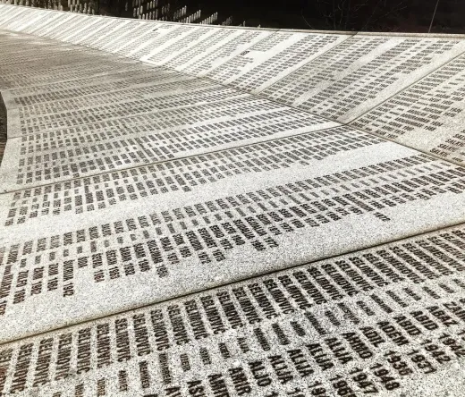A curved memorial wall inscribed with numerous names and dates.