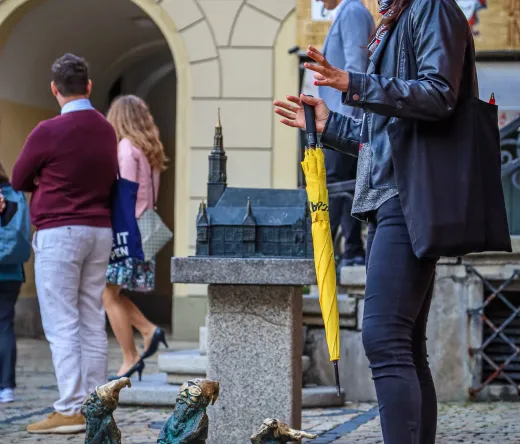 A tour guide in Wroclaw, Poland, points out dwarf statues to a group of tourists.