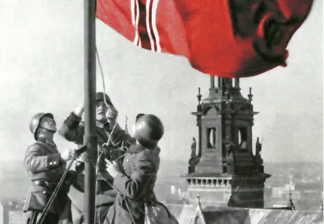 Soldiers raising a flag on a rooftop in Krakow.