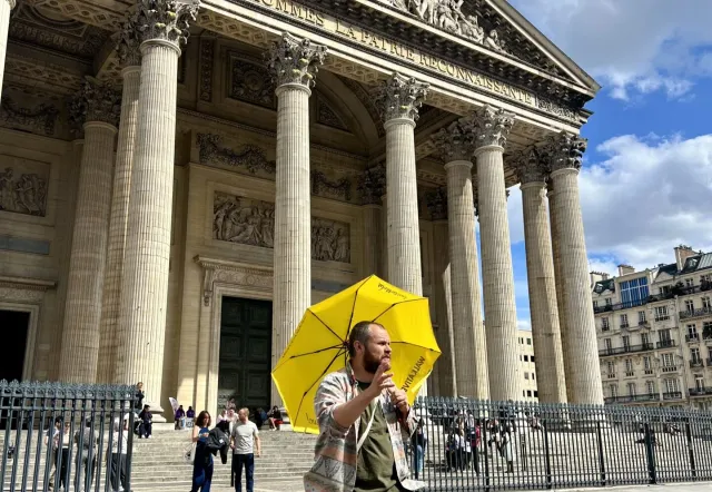 Un guía turístico dirige un grupo por el Barrio Latino de París, mostrando el Panteón.