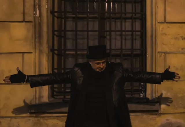 Reiseleiter mit Zylinder vor einem alten Gebäude.