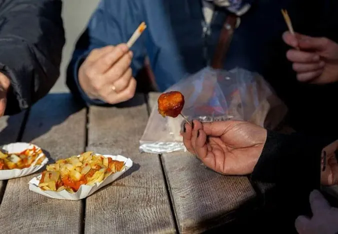 Tourists enjoying Currywurst in Berlin.