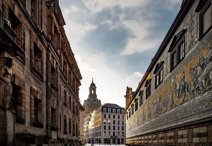 Calle empedrada en Dresde, Alemania, con edificios históricos y un fresco.