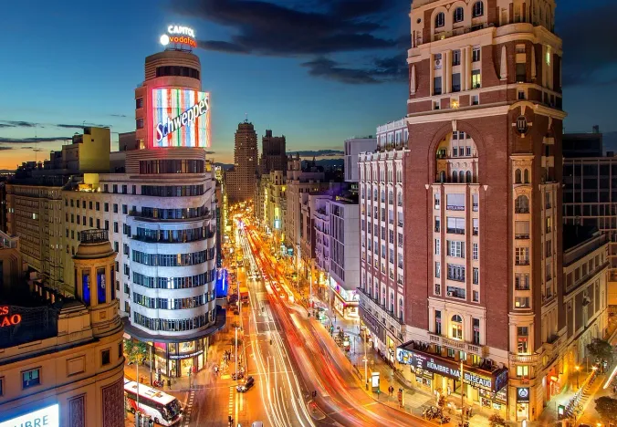 Night view of Madrid's Gran Vía, showcasing its vibrant architecture and bustling street life.
