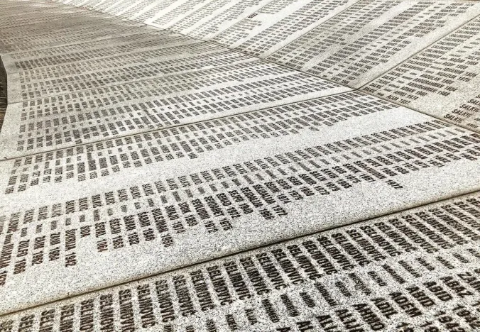 Un muro conmemorativo curvado con numerosos nombres y fechas.