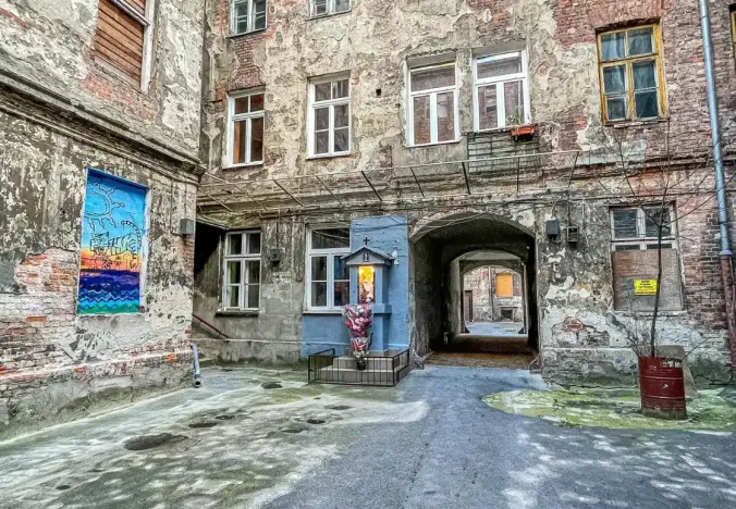Entdecken Sie einen versteckten Warschauer Innenhof mit alten Backsteingebäuden, Street Art und einem kleinen Schrein.