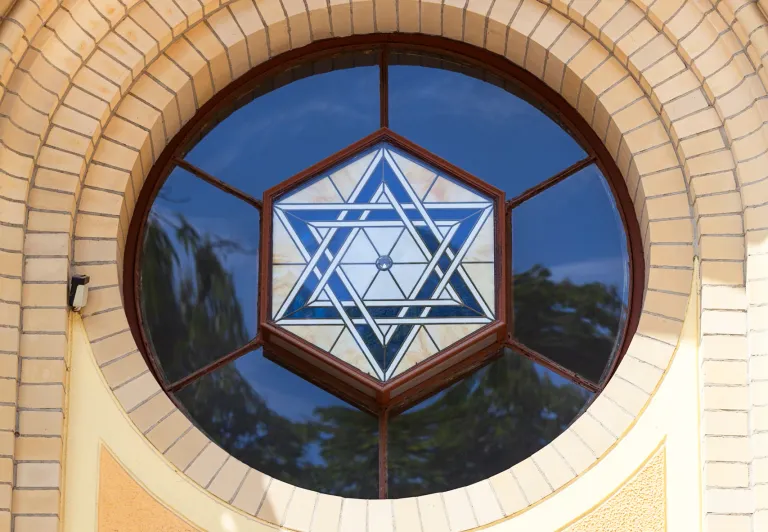 Nahaufnahme eines wunderschönen Buntglas-Davidsterns in einem runden Fenster eines Gebäudes in Wrocław, Polen.