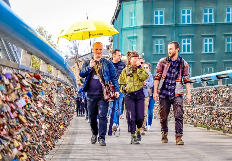 Grupa z wycieczki Walkative zwiedza Kraków, spacerując po moście pokrytym kłódkami miłości.