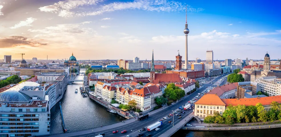 Panoramiczny widok na panoramę Berlina o zachodzie słońca, z charakterystycznymi zabytkami.