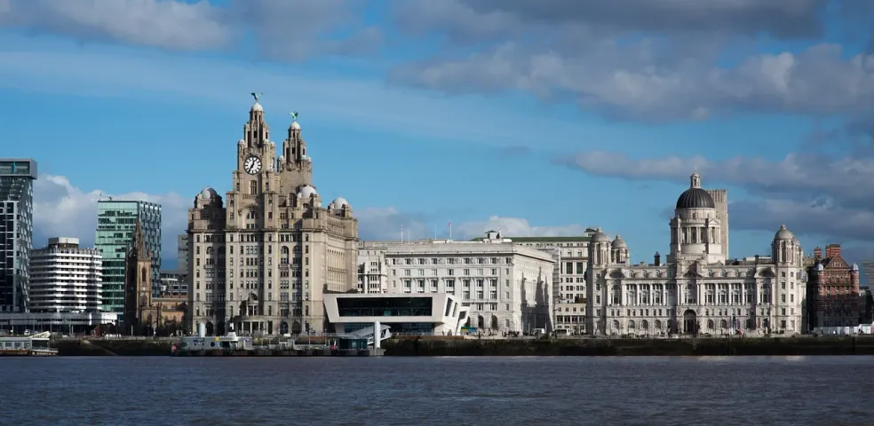 Nabrzeże Liverpoolu z Royal Liver Building, Cunard Building i Port of Liverpool Building pod częściowo zachmurzonym niebem.