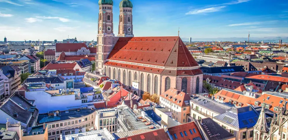 Aerial view of Munich's Frauenkirche (Cathedral of Our Blessed Lady) with its twin green domed towers, surrounded by city roo