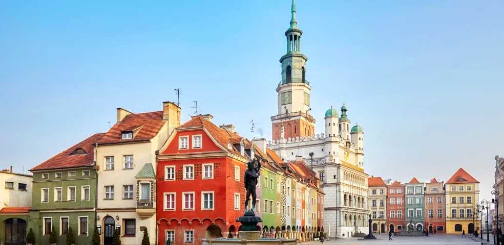 Cobblestone market square with a fountain and Apollo statue, colorful historic buildings, and a large town hall tower under a