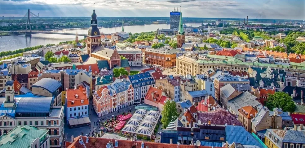 Vista aérea del casco antiguo de Riga con edificios coloridos, la aguja de la Iglesia de San Pedro, el río Daugava y el Puent