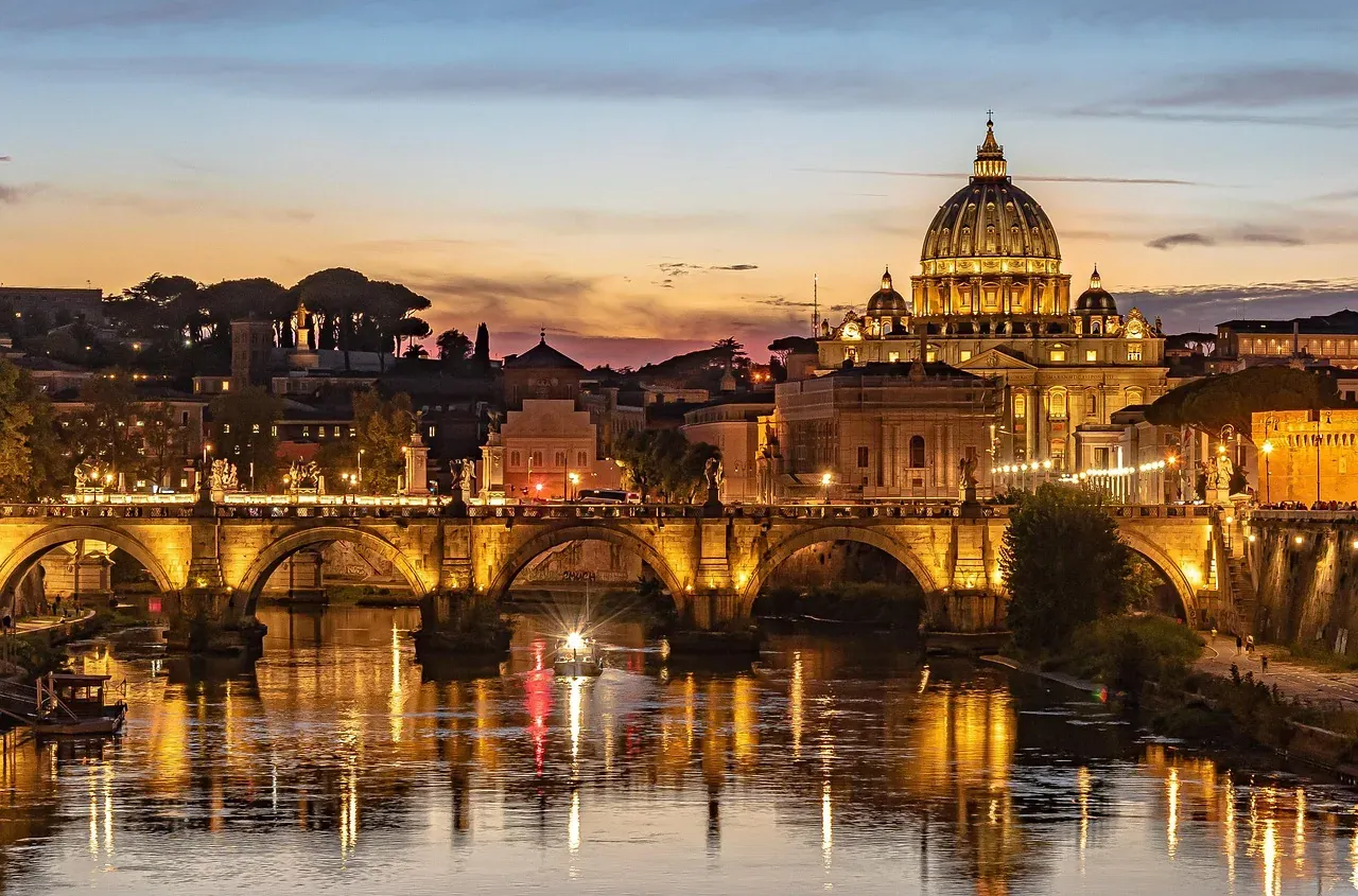 Impresionante vista al atardecer de la Basílica de San Pedro y el Ponte Sant'Angelo en Roma.