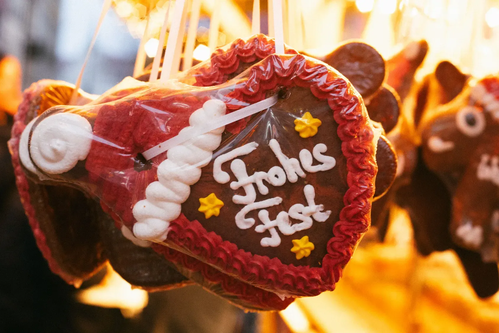 Verziertes Lebkuchenherz mit der Aufschrift „Frohes Fest“ an einem Weihnachtsmarktstand.