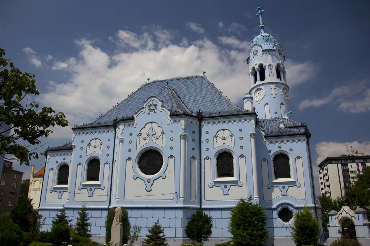 La Iglesia de Santa Isabel, conocida como la Iglesia Azul, con techo y torre azules, bajo un cielo nublado.