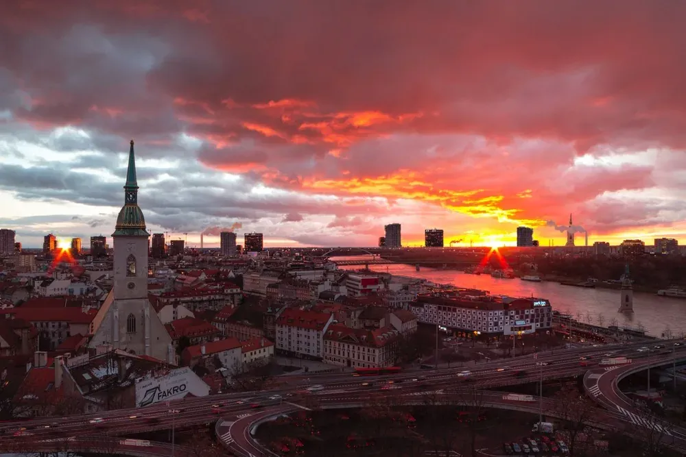 Vista aérea de Bratislava al atardcer con la Catedral de San Martín, el río Danubio, puentes y el horizonte urbano bajo un...