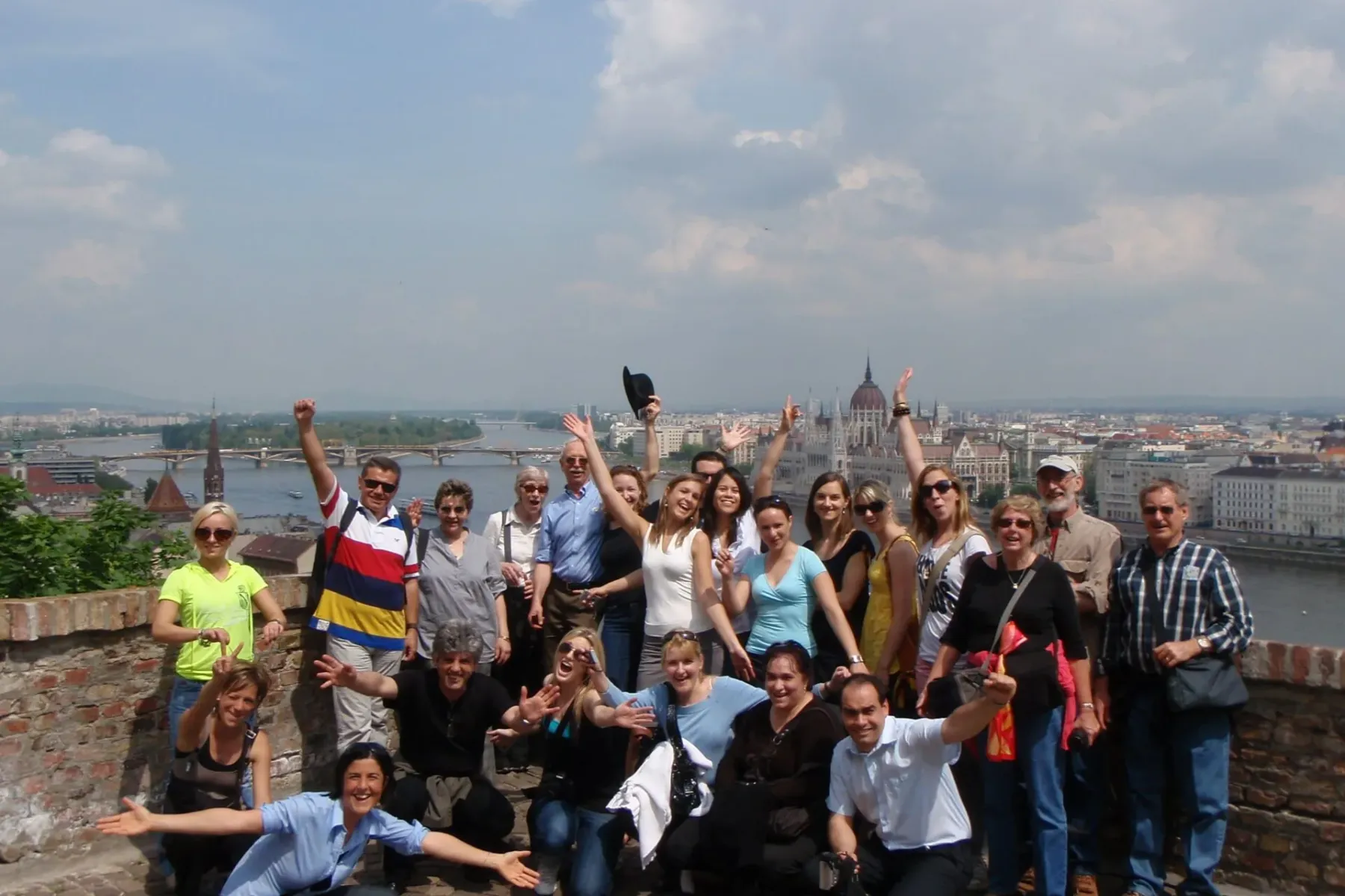 Group of tourists posing for a photo on a viewpoint overlooking the Danube river and the Hungarian Parliament Building in ...