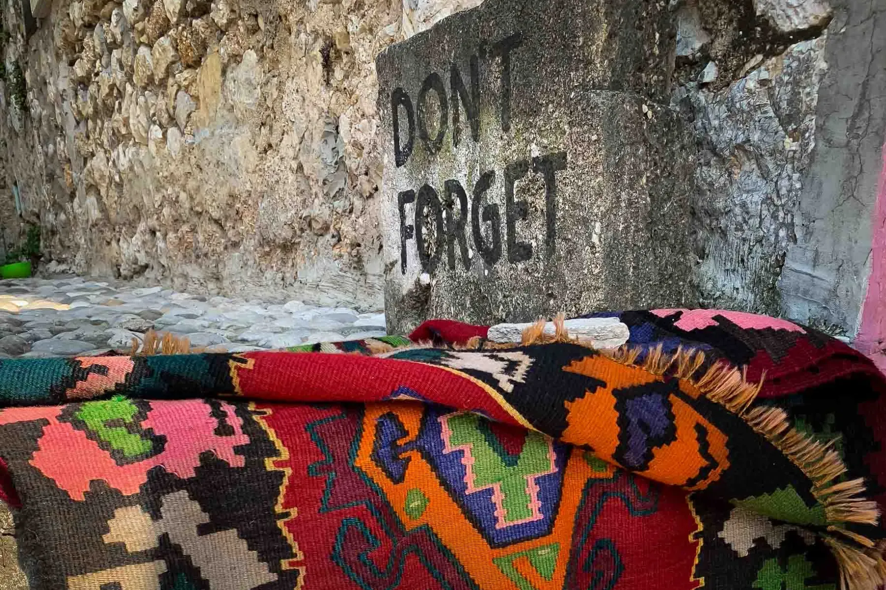 Kolorowy dywan w Berat, Albania, obok kamiennego muru.