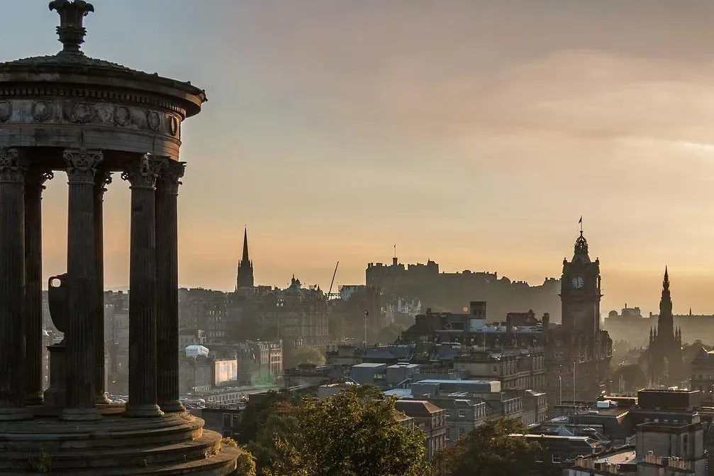Dugald-Stewart-Denkmal auf dem Calton Hill in Edinburgh bei Sonnenaufgang, mit Stadtpanorama, Schloss und Denkmälern.