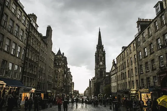 Straßenszene in Edinburghs Old Town, mit historischen Steingebäuden an einer Kopfsteinpflasterstraße, die zur Tron Kirk fü...