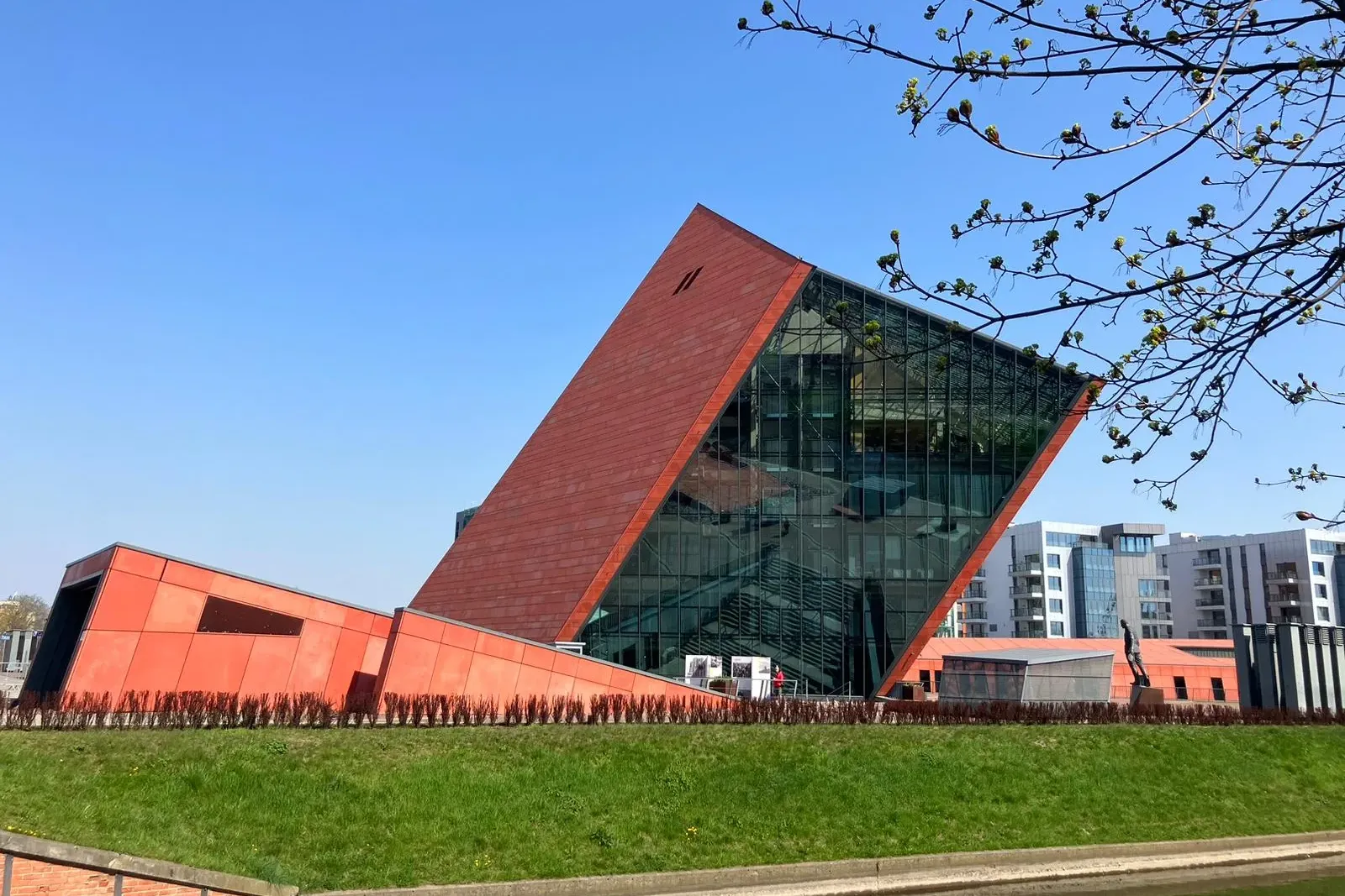 Außenansicht des Museums des Zweiten Weltkriegs in Danzig, ein modernes Gebäude mit roten und gläsernen Fassaden, am Kanal.