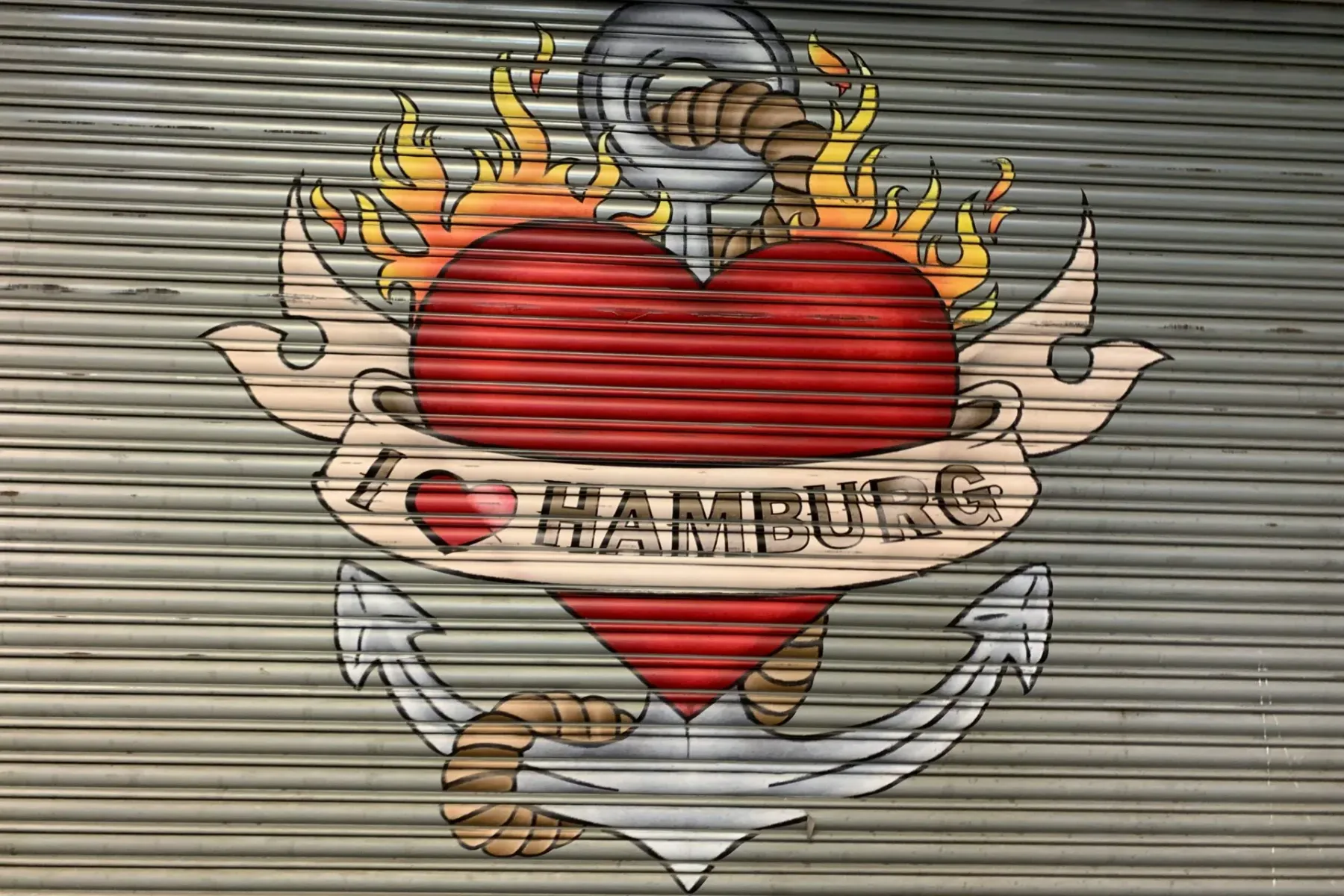 Mural en una puerta enrollable de metal corrugado que muestra un corazón rojo, un ancla, llamas y el texto "I ♥ HAMBURG".