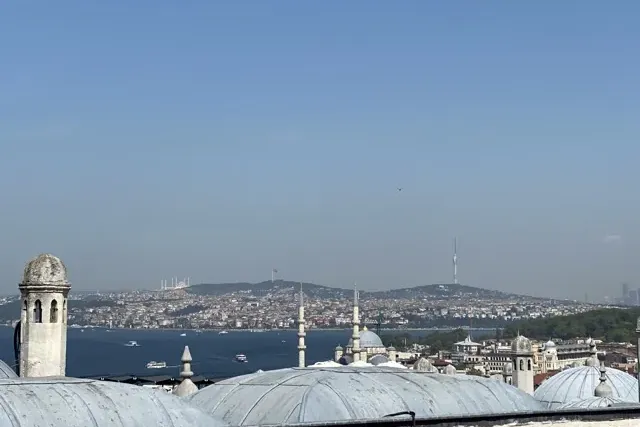 Vista de Estambul sobre el Bósforo, mostrando edificios de la ciudad, mezquitas distantes en colinas y barcos en el agua b...