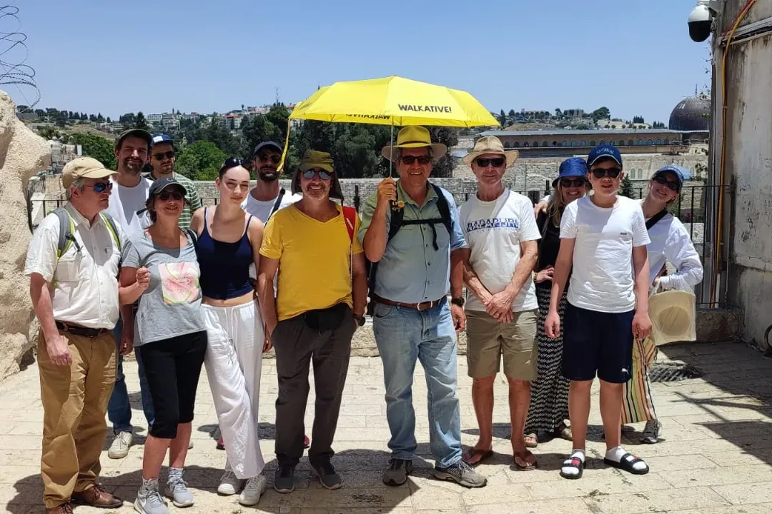 Un grupo de turistas con un guía de Walkative sosteniendo un paraguas amarillo en un día soleado en Jerusalén, con la Cúpu...