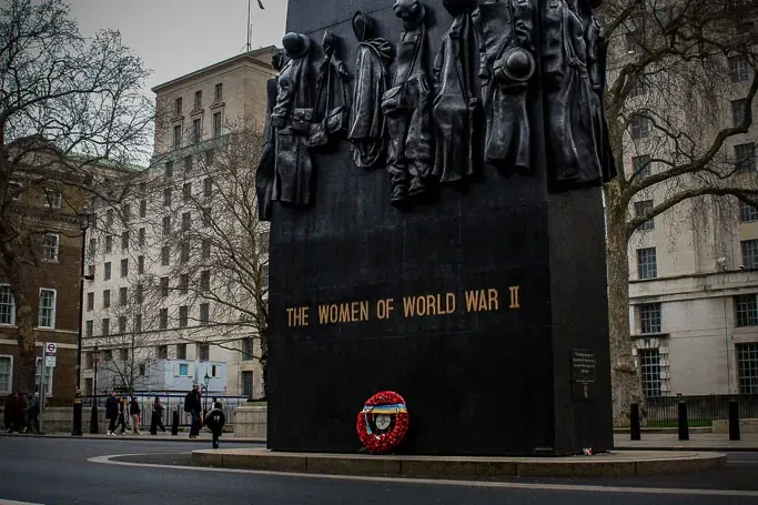 Pomnik Kobiet II Wojny Światowej w Londynie, duży czarny monument z brązowymi figurami, widziany z perspektywy ulicy.