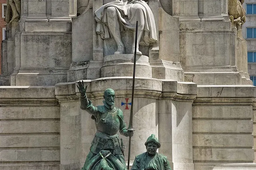 Monumento con una estatua de piedra sentada de Cervantes, y estatuas de bronce de Don Quijote a caballo y Sancho Panza en ...