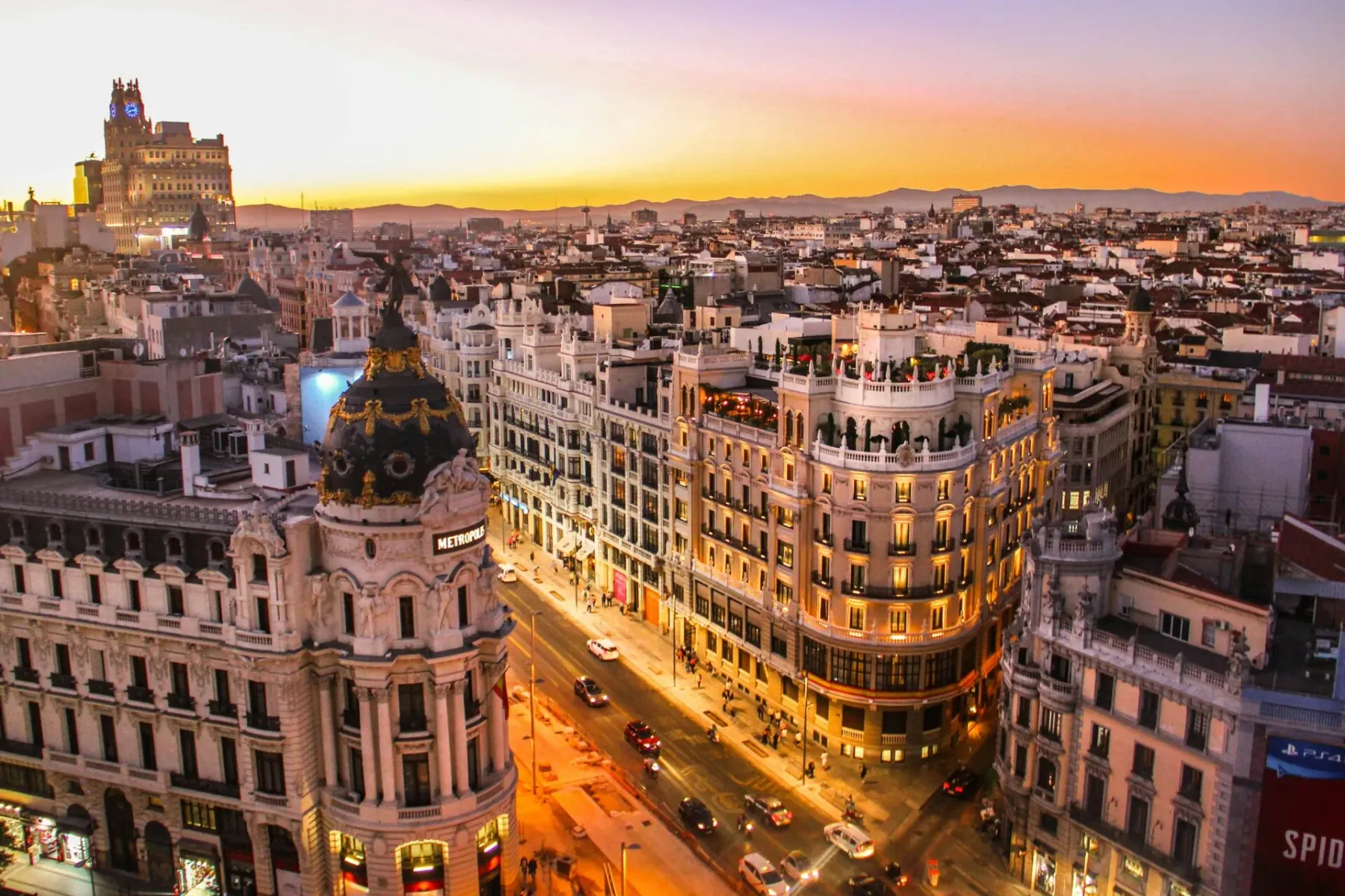 Vista aérea de Madrid al atardecer. El ornamentado Edificio Metrópolis con su cúpula es prominente, con coches y peatones ...