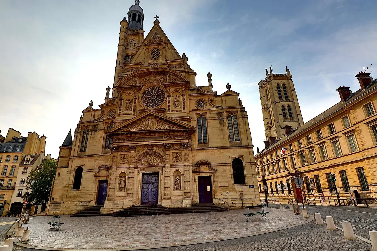Die verzierte Fassade der Kirche Saint-Étienne-du-Mont in Paris, mit einem Uhrturm und Buntglasfenstern, unter einem teilw...