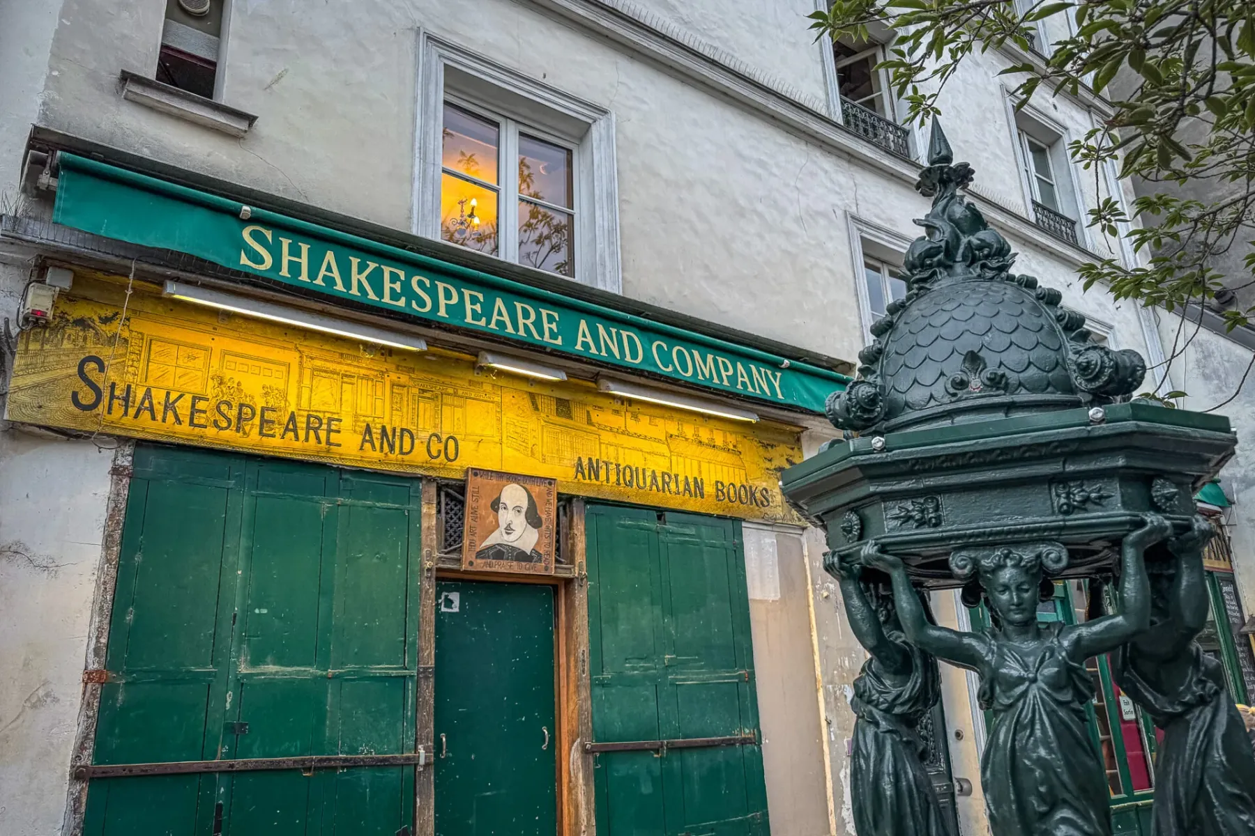 Außenansicht der Buchhandlung Shakespeare and Company in Paris, mit grüner Markise, gelber Fassade und einem dunkelgrünen ...