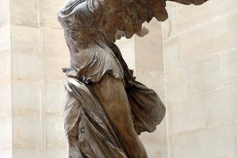 Große Marmorstatue der Nike von Samothrake, kopflos und armlos, in fließendem Gewand, auf einem Sockel.