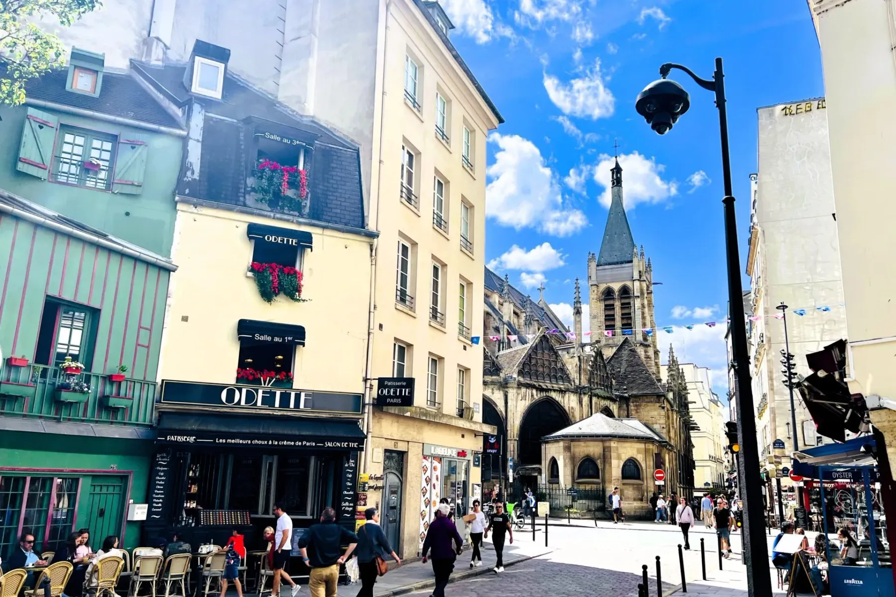 Kopfsteingepflasterte Straße in Paris mit historischen Gebäuden, Odette Patisserie und dem Turm der Kirche Saint-Séverin. ...