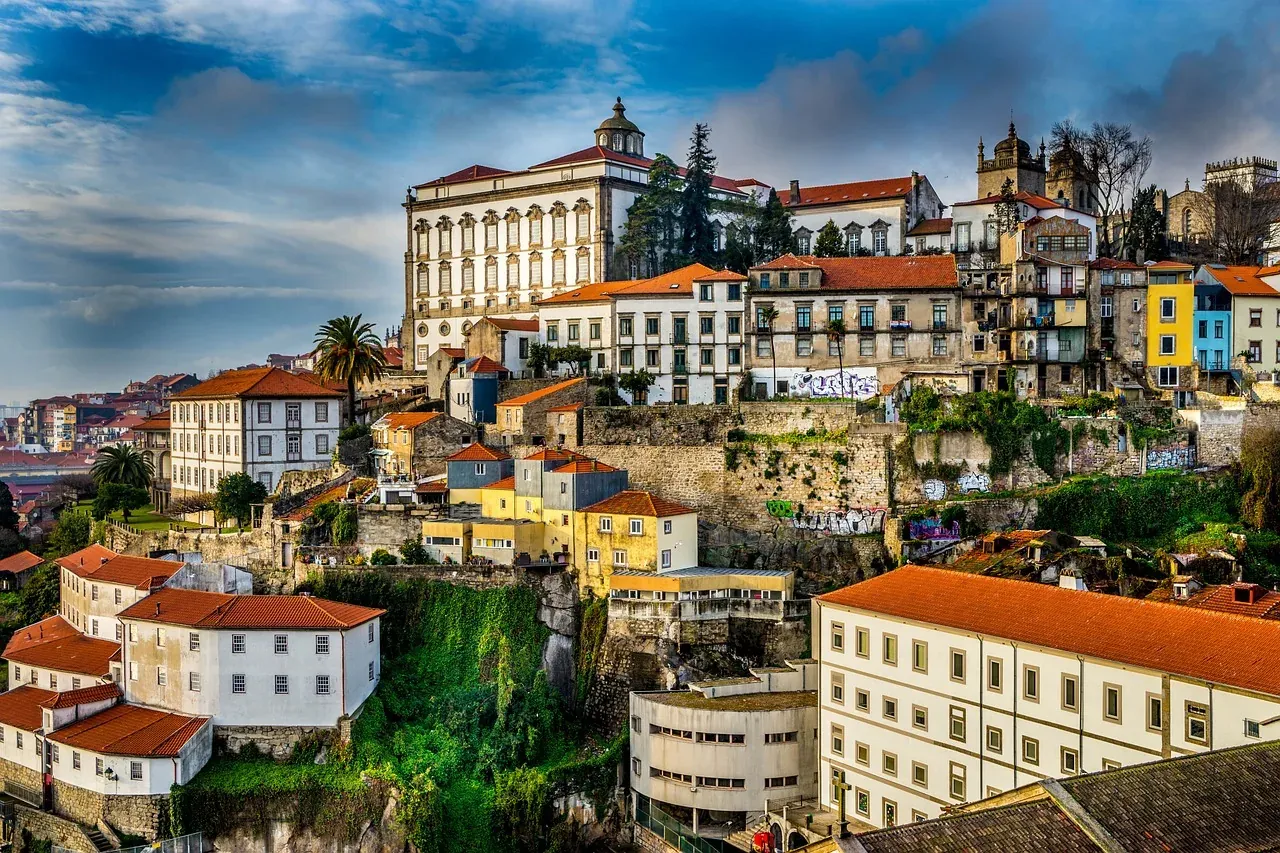 Historische Stadtansicht von Porto mit traditionellen Gebäuden, roten Ziegeldächern und einem großen weißen palastartigen ...