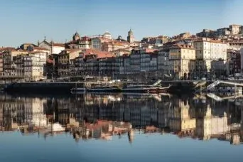 Edificios históricos coloridos del barrio de la Ribeira de Oporto bordean el río Duero, reflejándose en sus aguas tranquilas.