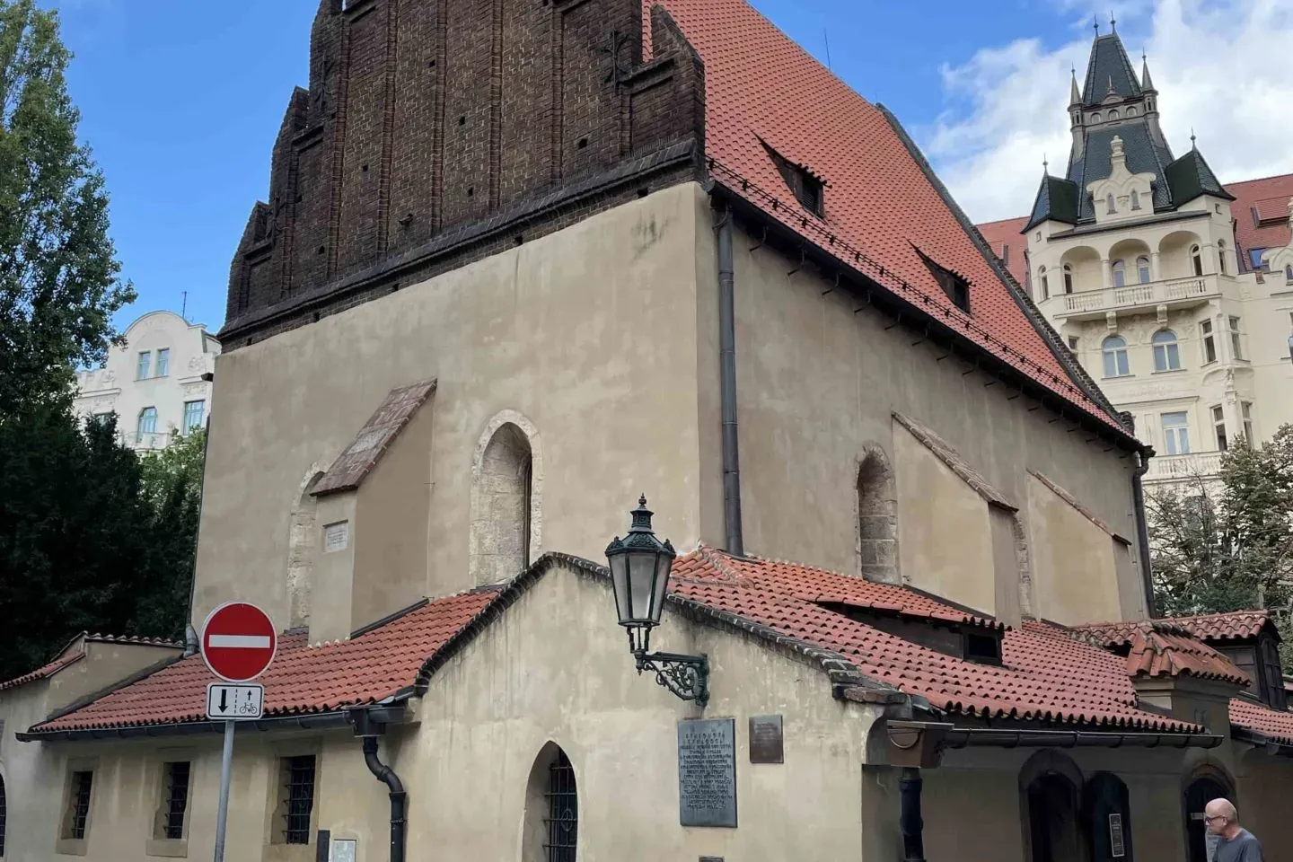 Exterior de la Sinagoga Vieja-Nueva en Praga con gablete de ladrillo, techo de terracota y fachada de estuco, una persona ...