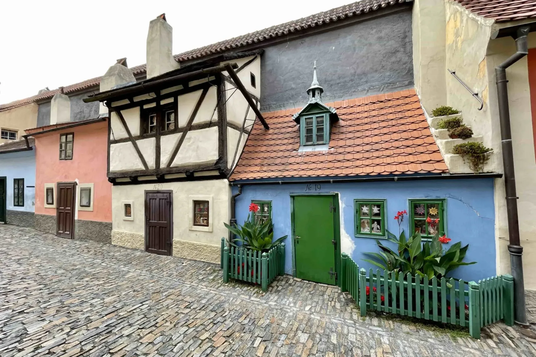 Casas históricas coloridas con tejados de tejas a lo largo de una estrecha calle empedrada, incluyendo una casa azul con p...