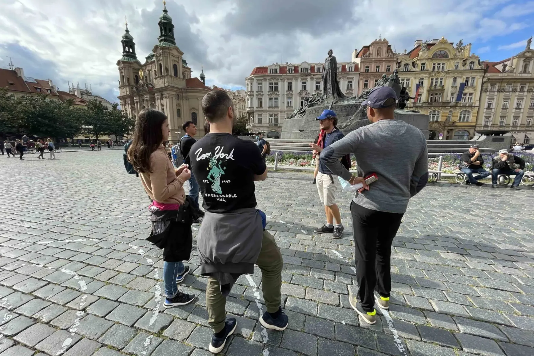 Un pequeño grupo de personas escuchando a un guía en la Plaza de la Ciudad Vieja de Praga, con la Iglesia de San Nicolás y...