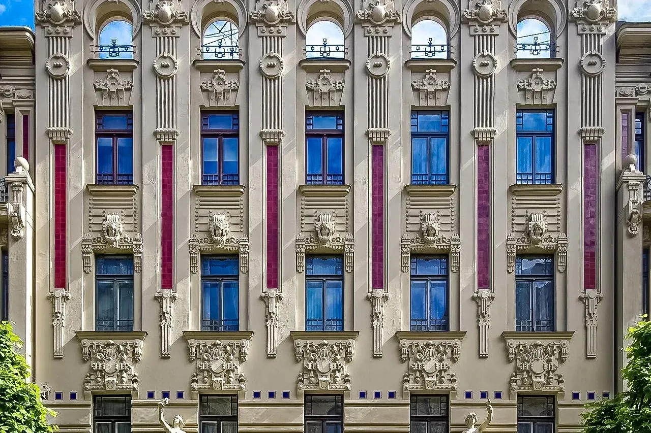 Aufwendige Jugendstilfassade in Riga mit detailreichen Skulpturen, verzierten Fenstern, vertikalen roten Akzenten und zwei...