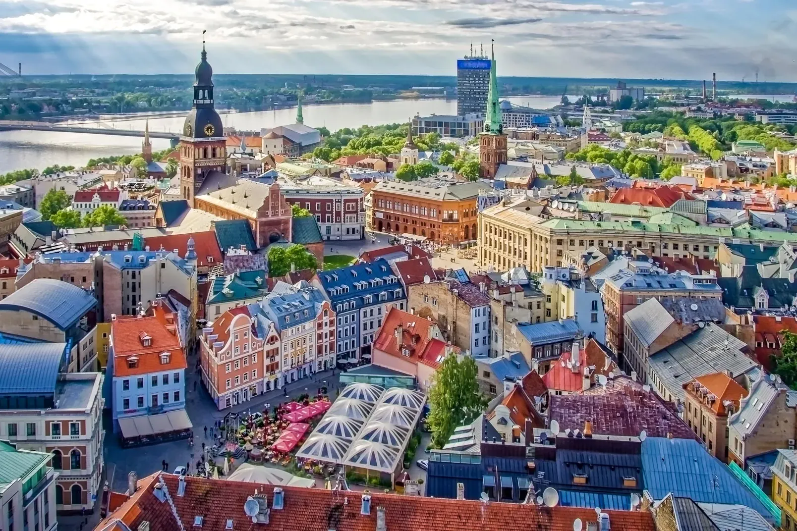 Luftaufnahme der Rigaer Altstadt mit farbenfrohen Gebäuden, dem Turm der Petrikirche, dem Fluss Düna und der Vansu-Brücke.