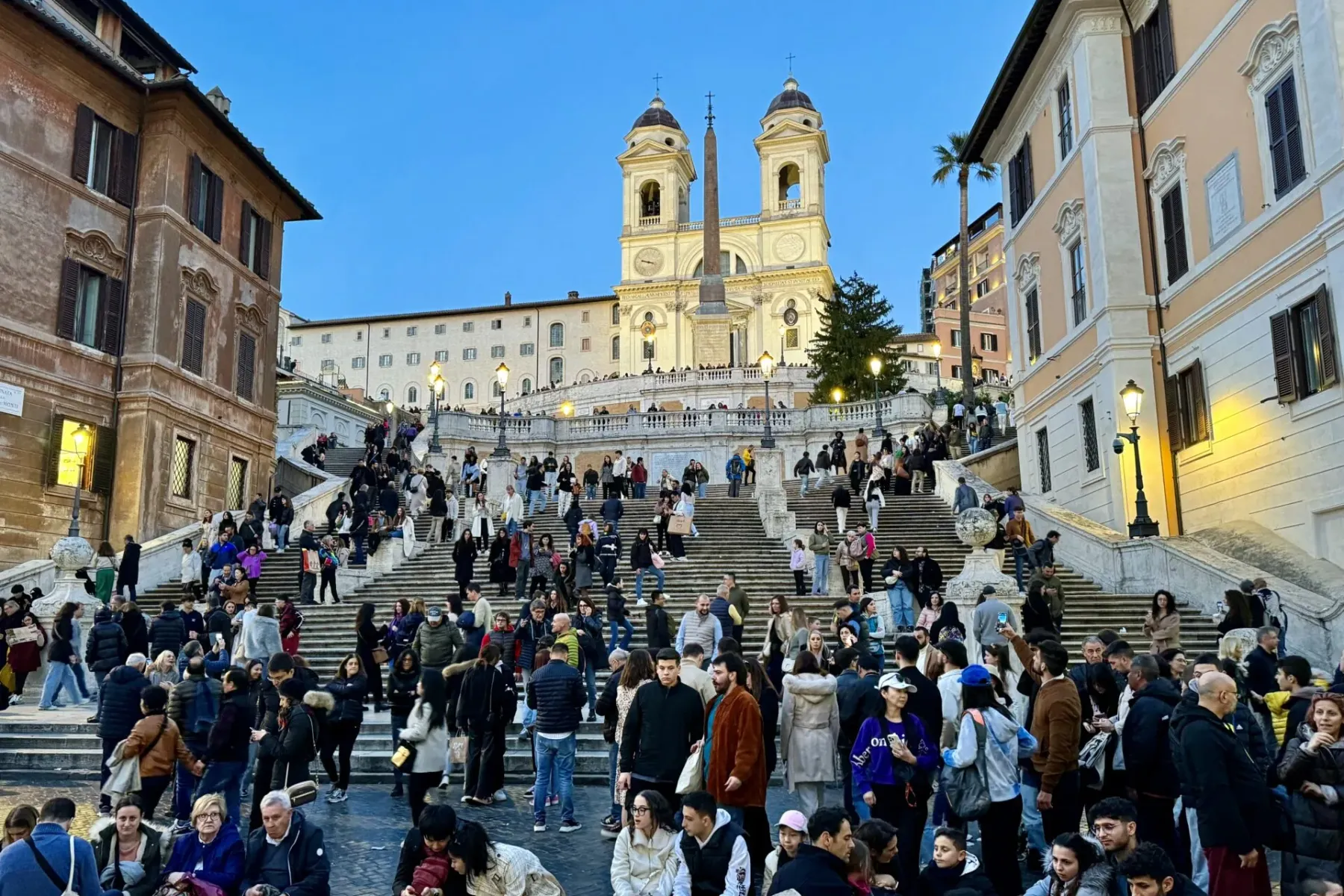 Turistas disfrutando de la Escalinata Española en Roma al atardecer.