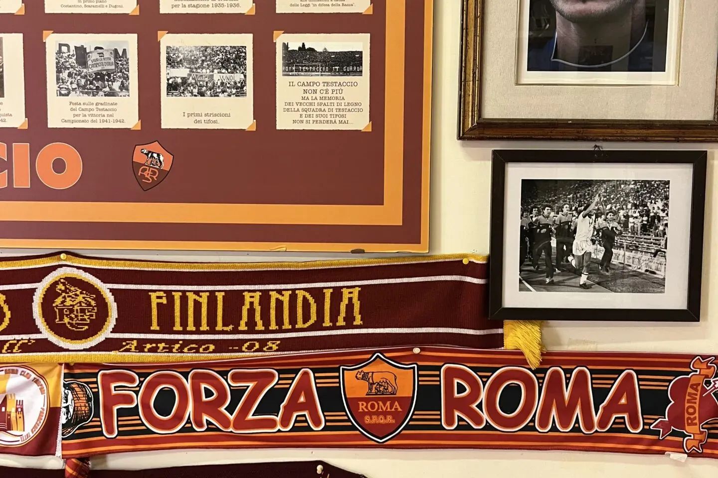 Wanddisplay mit Fanartikeln des Fußballvereins AS Rom: Schals, ein Porträt von Francesco Totti und historische Fotos.