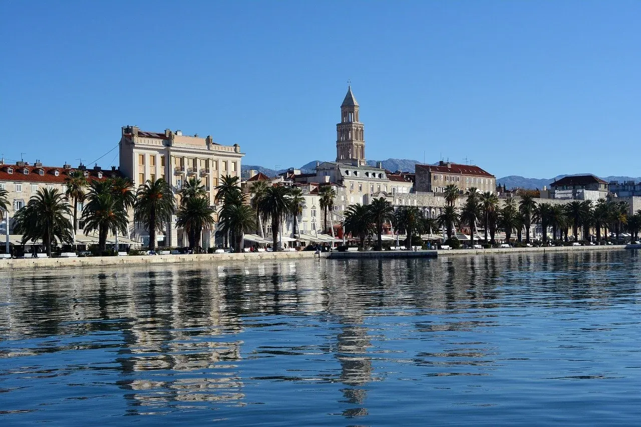 Vista del paseo marítimo Riva de Split con palmeras, edificios históricos, el campanario de la Catedral y mar en calma ref...