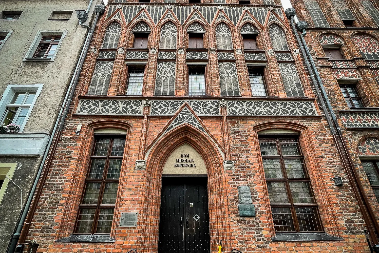 Das gotische Backsteinhaus von Nikolaus Kopernikus in Toruń, mit Treppengiebel und verzierten Fenstern, von unten gesehen....