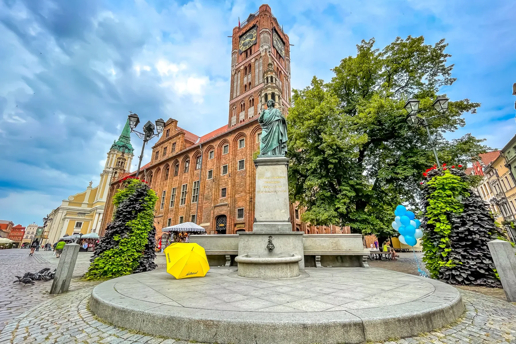 Das Alte Rathaus in Thorn, ein rotes Backsteingebäude mit Uhrturm, steht hinter dem Nikolaus-Kopernikus-Denkmal.
